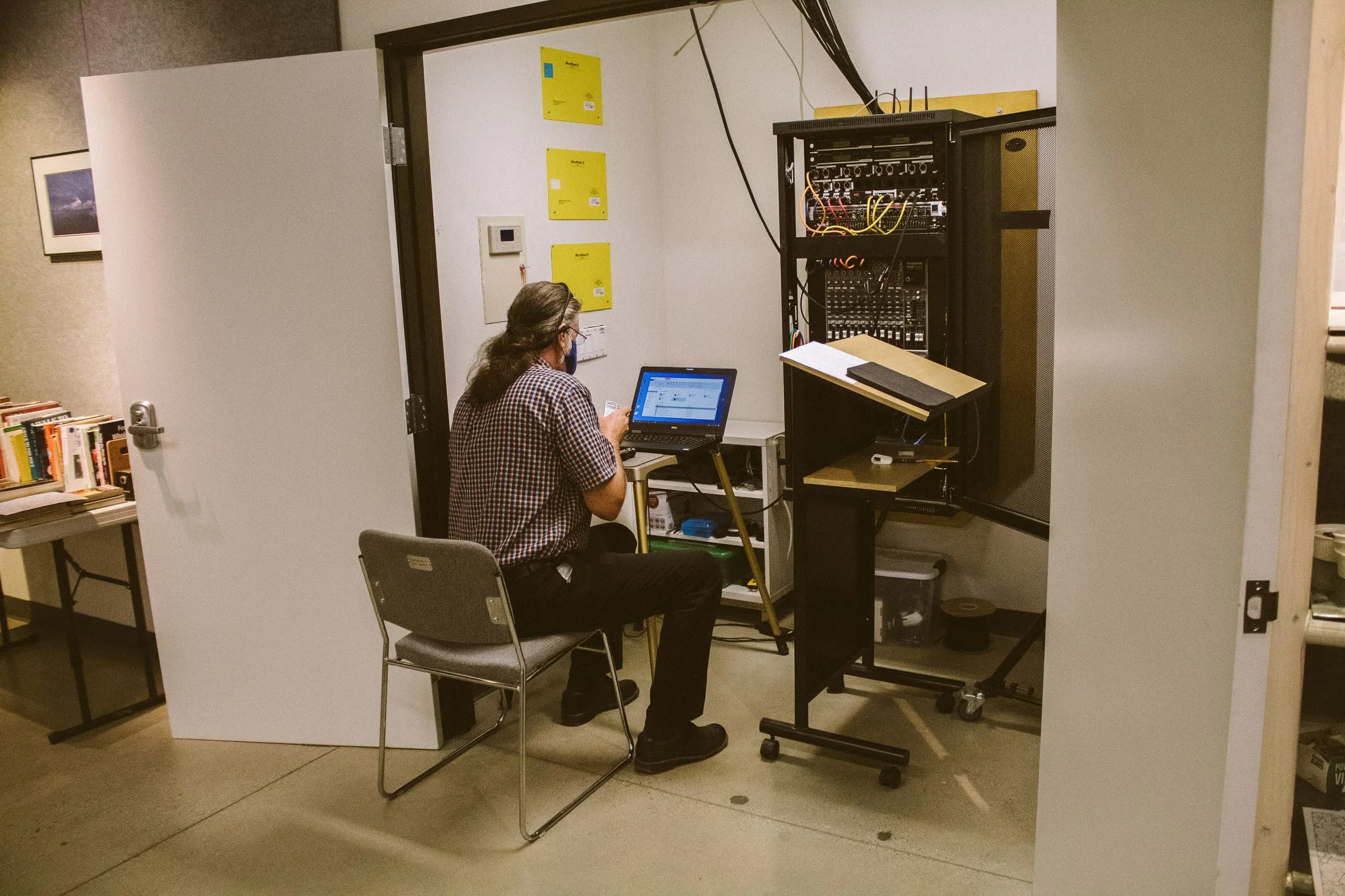 A technician with a laptop next to a network cabinet in a technical room