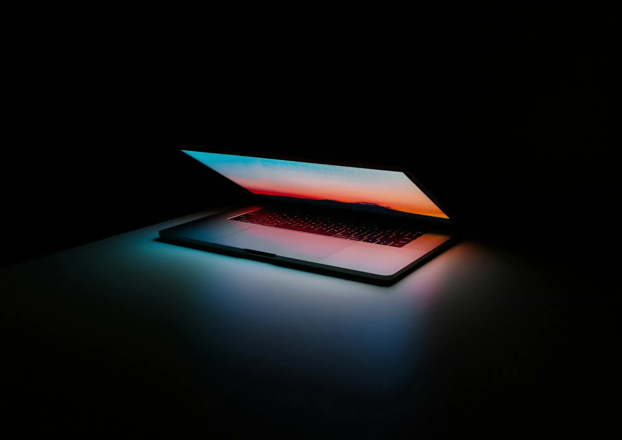 Uchylony laptop podświetlony w ciemnym pomieszczeniu