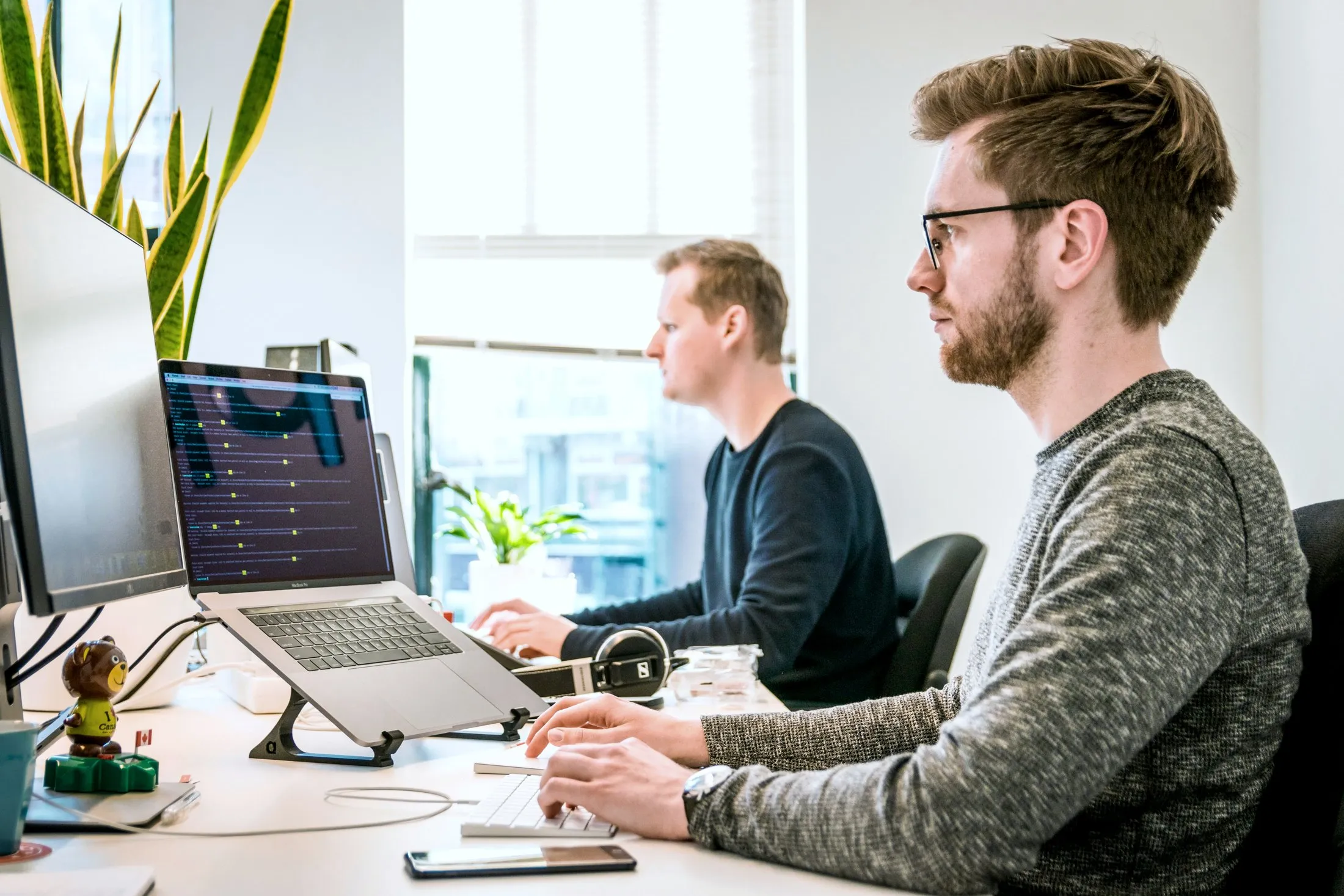 Two people working on laptops in the office