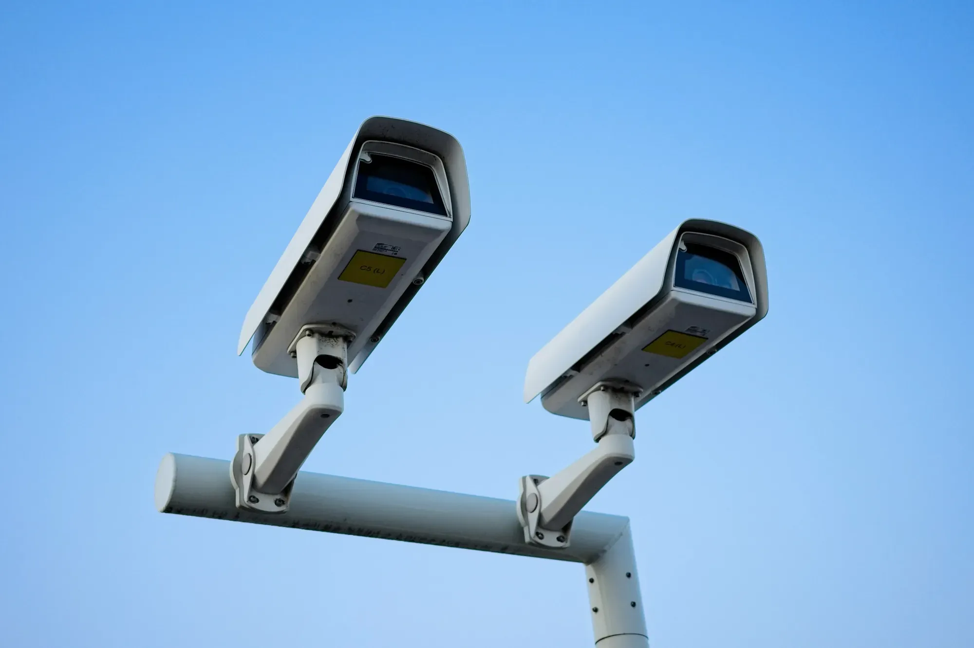 Dwie kamery monitoringu na wysięgniku na tle nieba