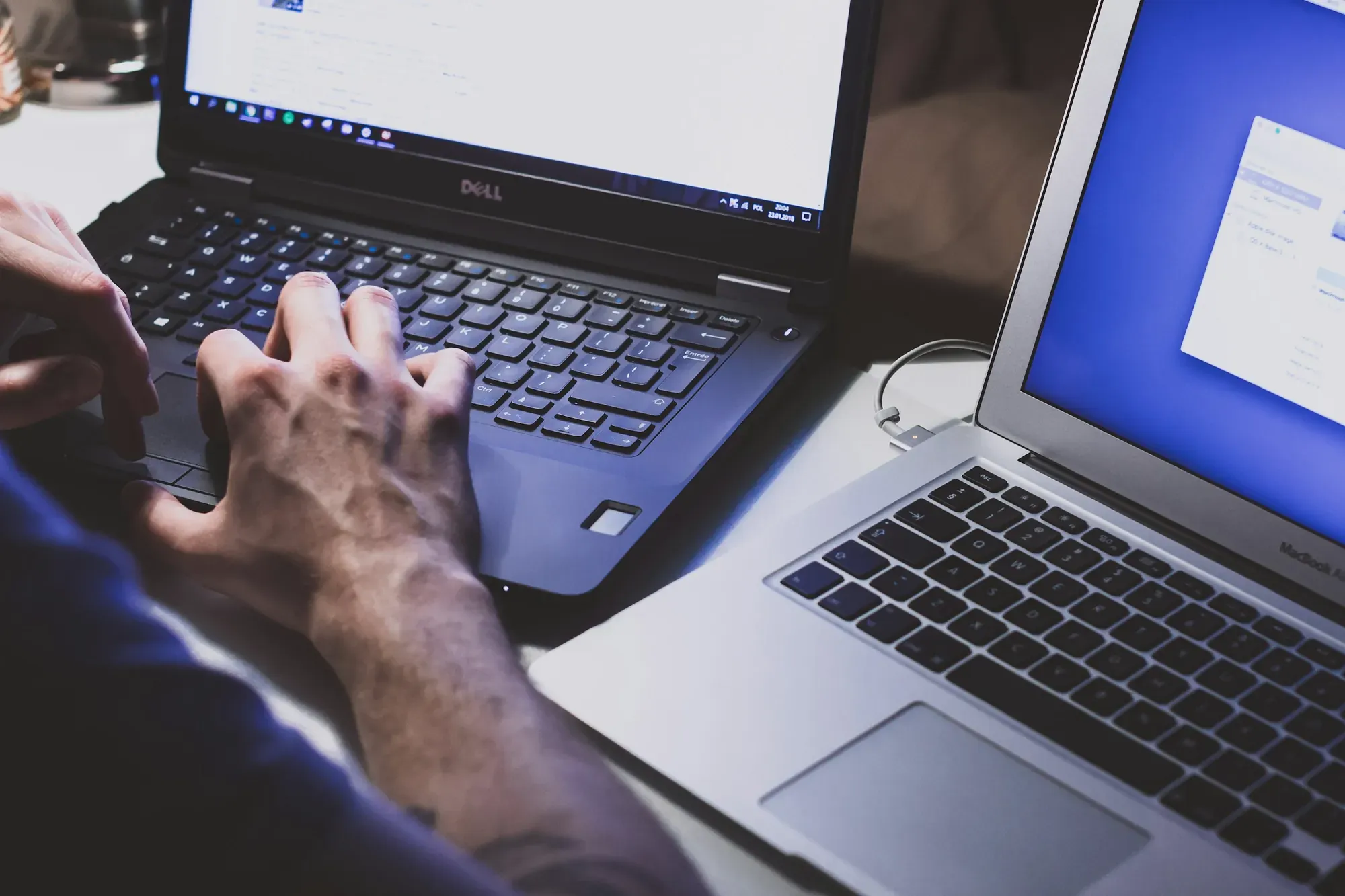 Dwie osoby pracujące na laptopach przy jednym biurku