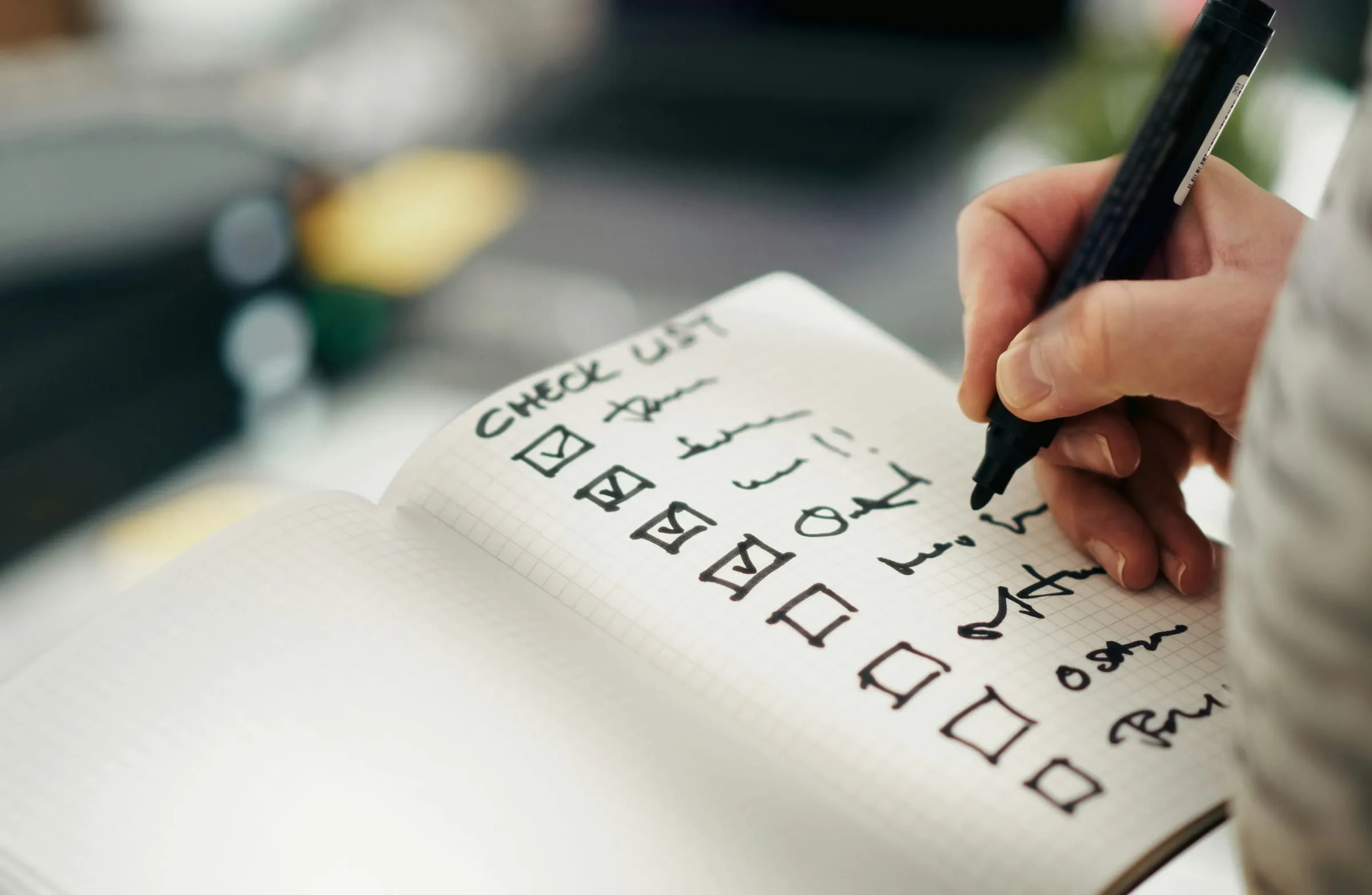 A hand ticking off items on a checklist in a notebook