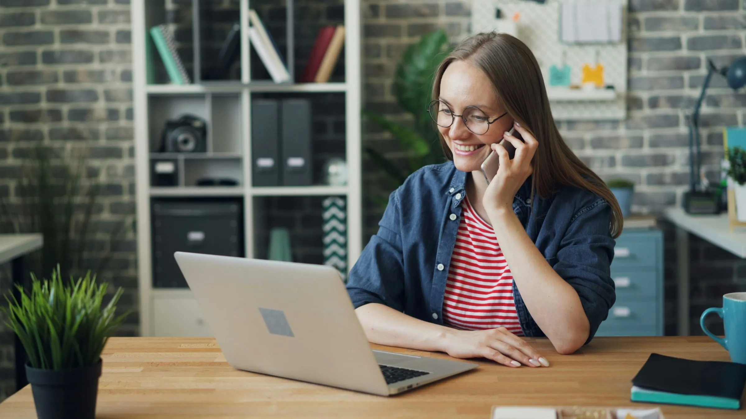 A woman on the phone at a desk with a laptop
