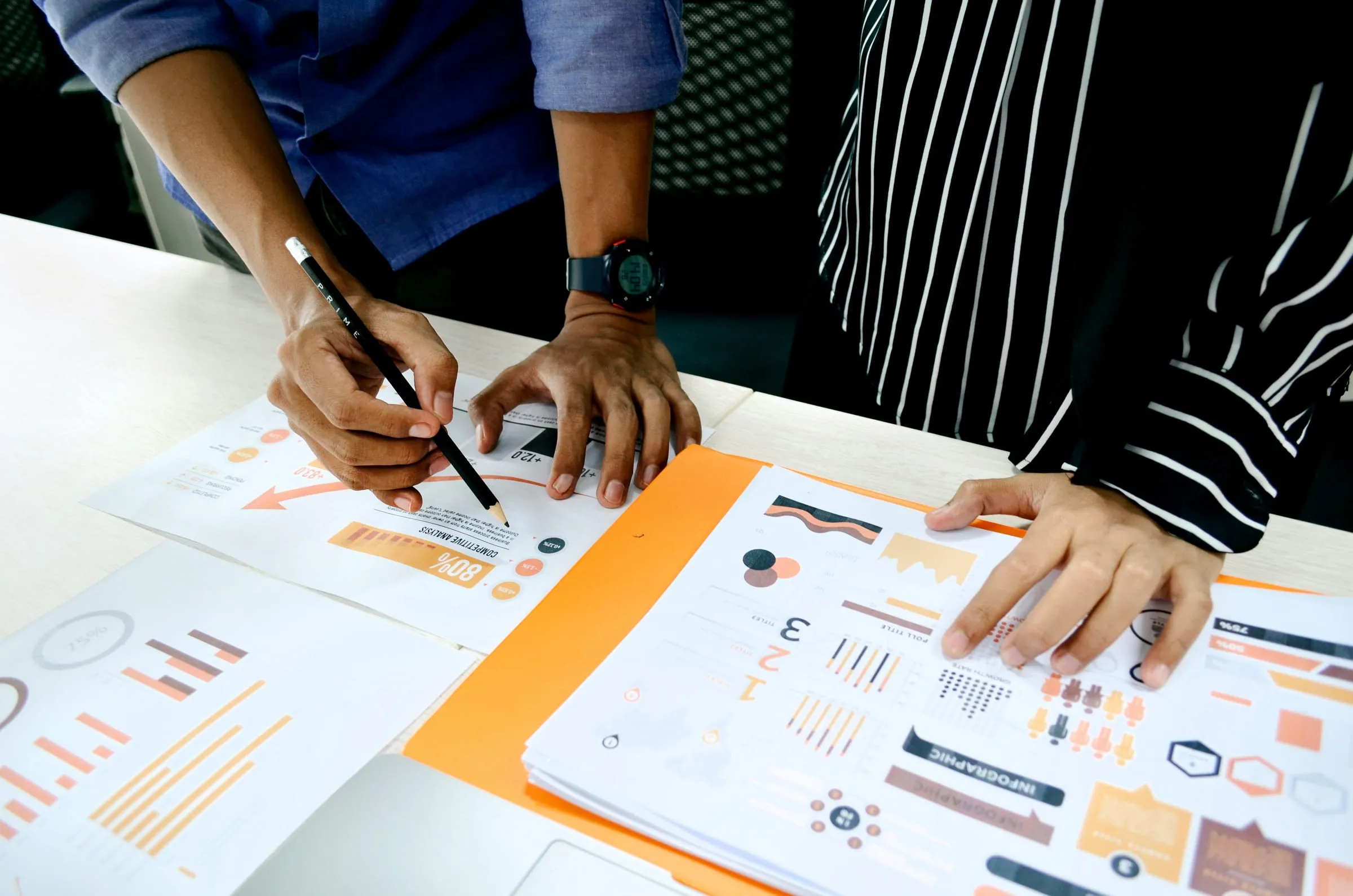 Two people analysing printed charts on a table