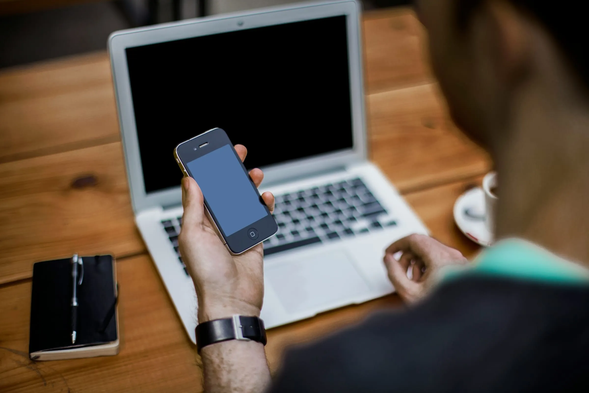 A person holding a phone over a laptop keyboard
