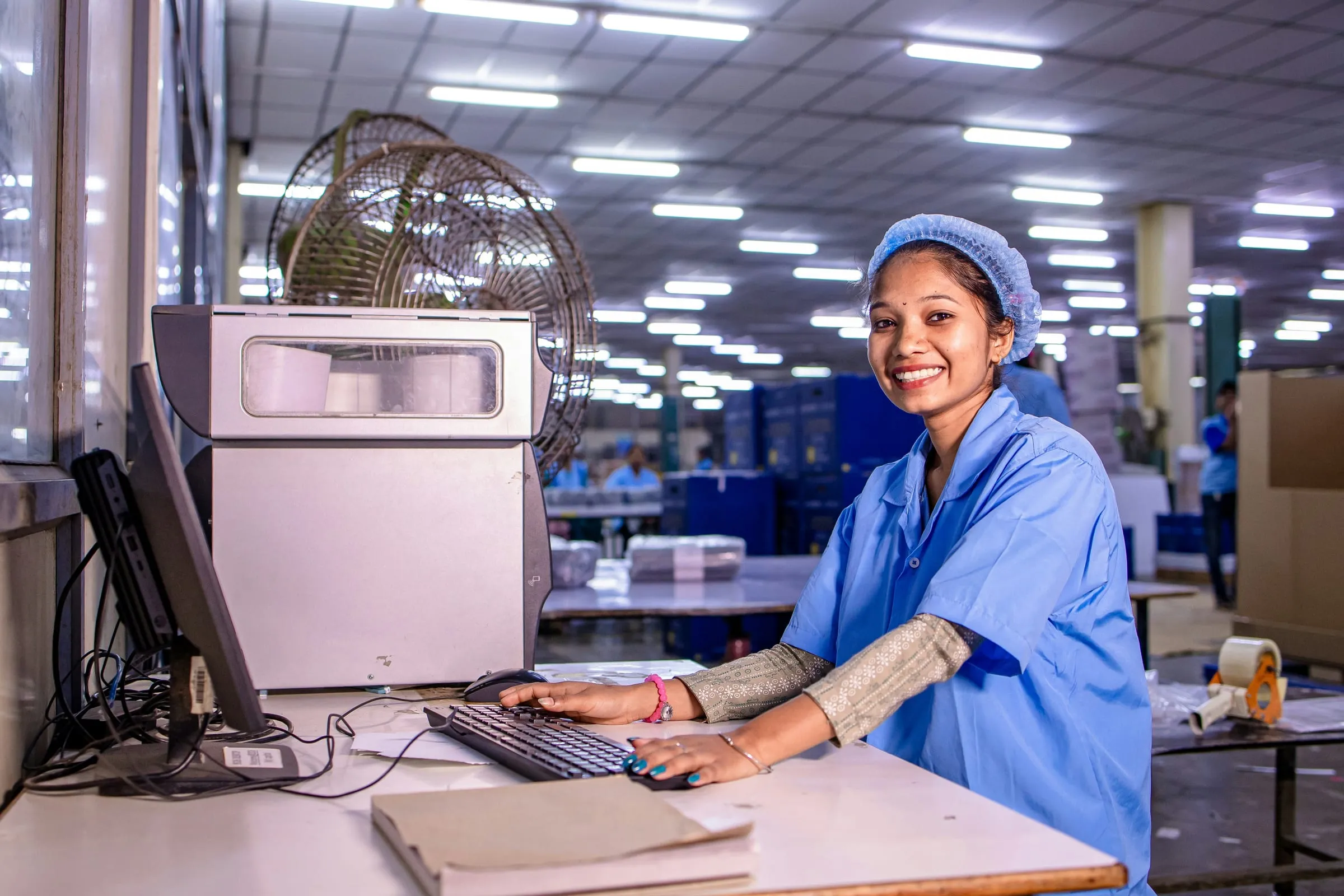 A production floor worker at a computer workstation with a label printer