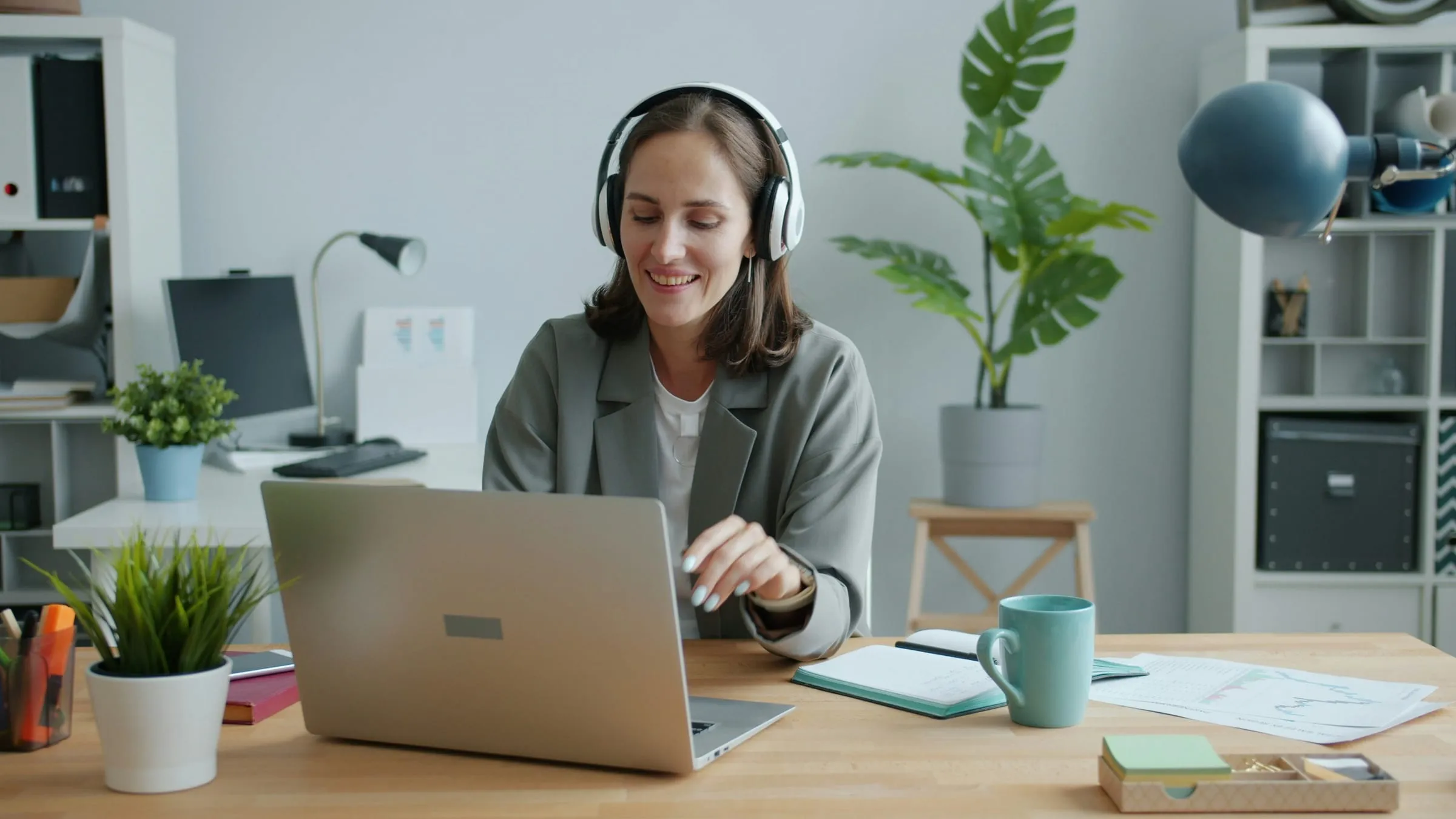 A woman wearing headphones working at a laptop in an office