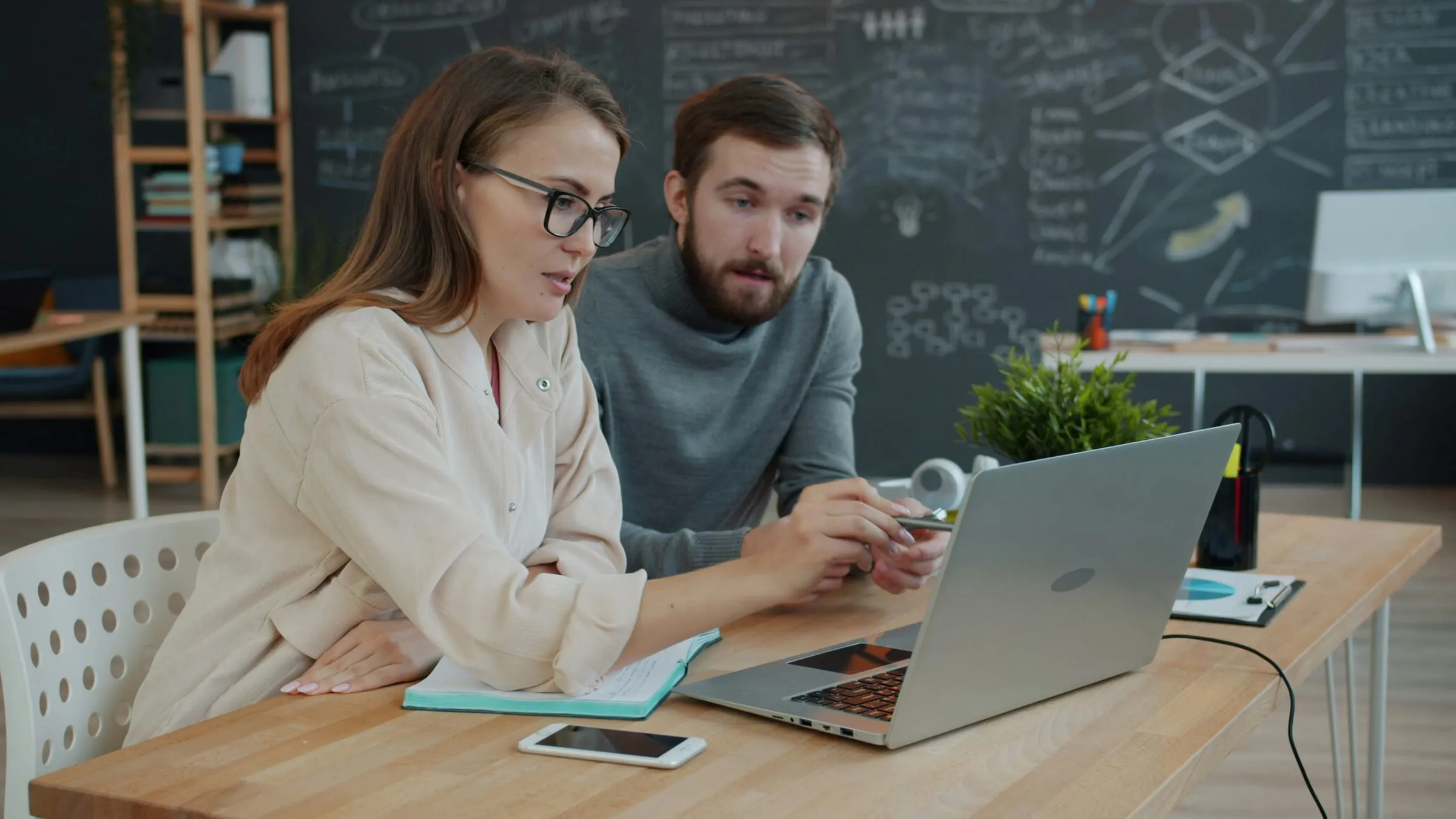 Two people working together at a laptop in an office